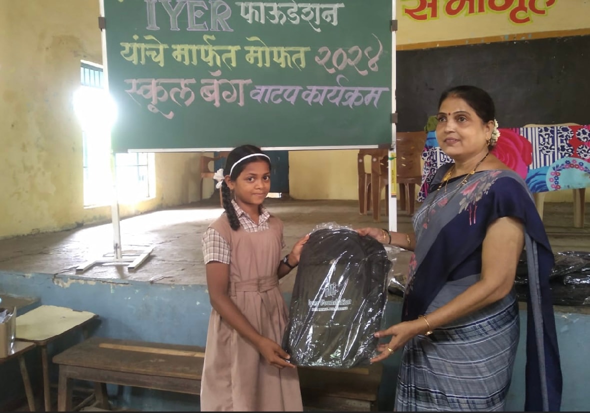 Girl receiving school bag from teacher at Iyer Foundation event