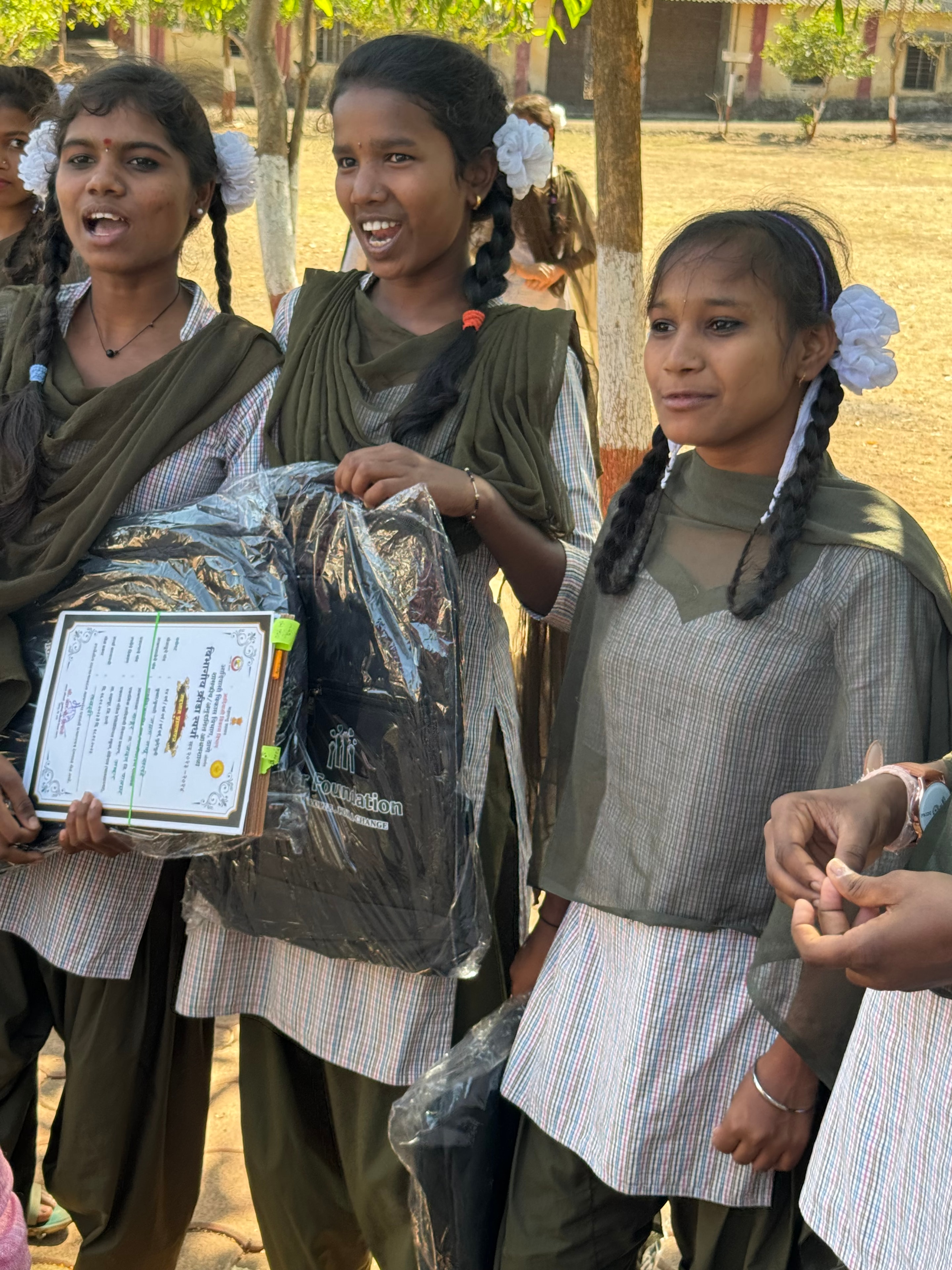 Girls holding Iyer Foundation bags and an award certificate