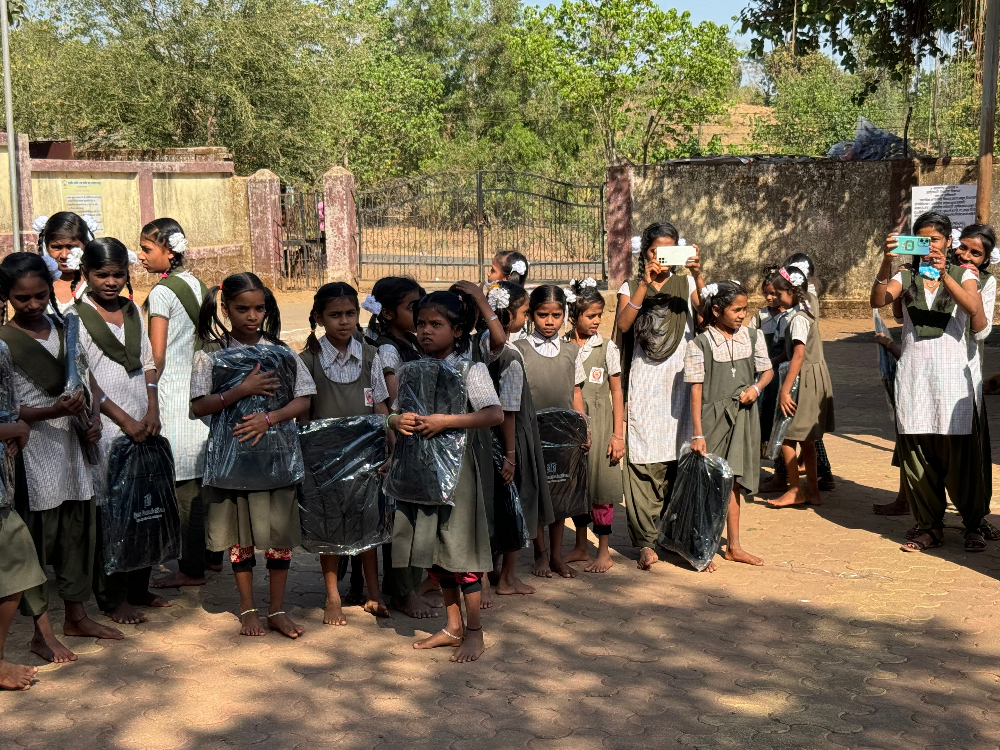 Girls lined up outdoors holding school bags from Iyer Foundation