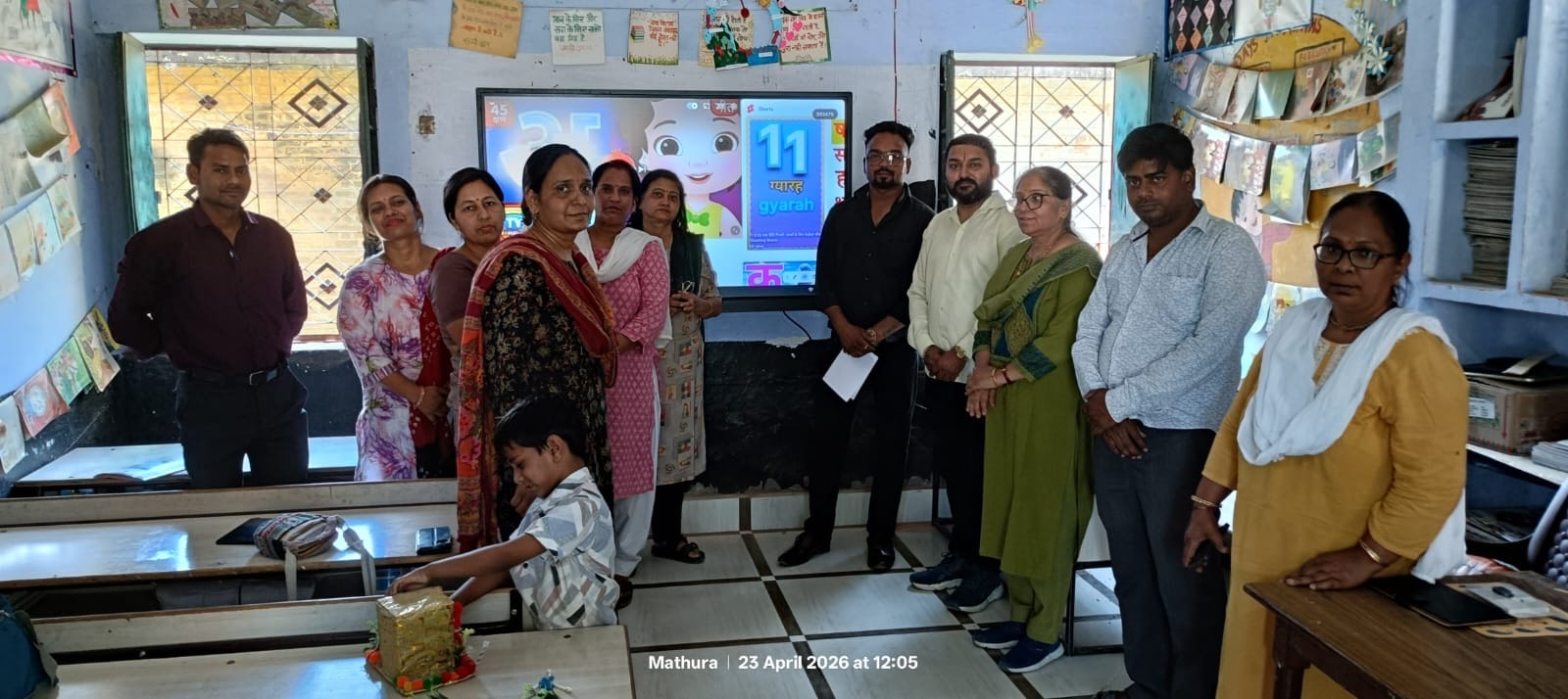 Teachers and community members gathered around a smart board showing educational content in Mathura