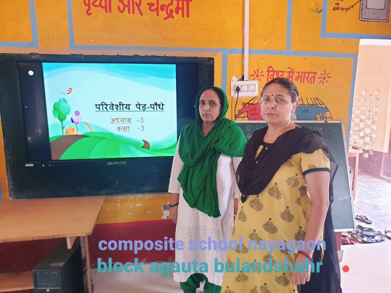 Two teachers standing beside a smart board at Composite School Nayagaon